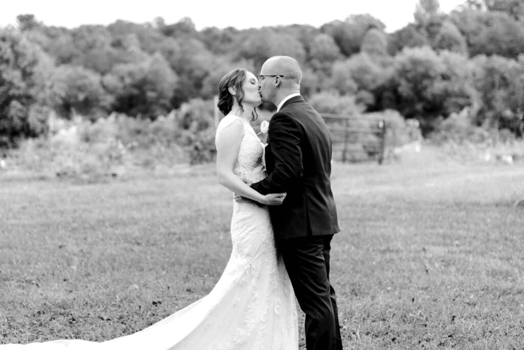 bride and groom kissing in field during first look in Charlottesville VA wedding